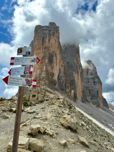 Hiking signs and dramatic peaks of Tre Cime di Lavaredo surrounded by clouds